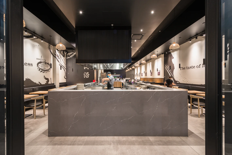 Mogouyan Hand-Pulled Noodle at West Edmonton Mall: the stone-clad service counter in front of the open kitchen, with large-format tile flooring running through the dining area.