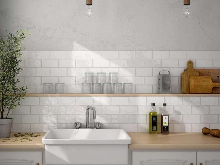A white subway tile backsplash above a farmhouse sink and a wooden countertop.