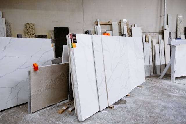 Slabs of white veined quartz and stone standing on edge in a fabrication warehouse.