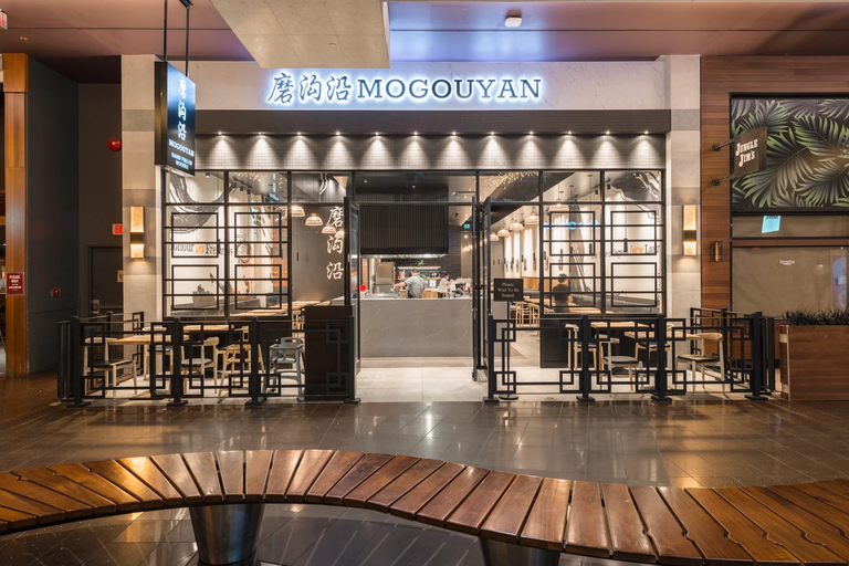 Mogouyan Hand-Pulled Noodle at West Edmonton Mall: the shopfront seen from the mall concourse under its sign, with a curved timber deck bench in the foreground.