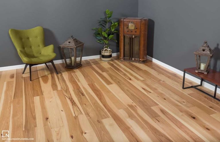 Light natural wood plank flooring in a styled room with a yellow armchair, plants and grey walls.