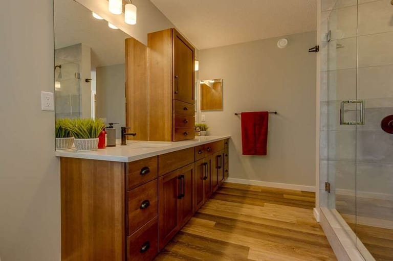 Liberty Showhome: an ensuite with a long warm-stained wood double vanity, a glass shower and a light plank floor.