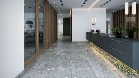 A hallway with grey marble-look large-format tile and a dark wall-mounted console with plants.