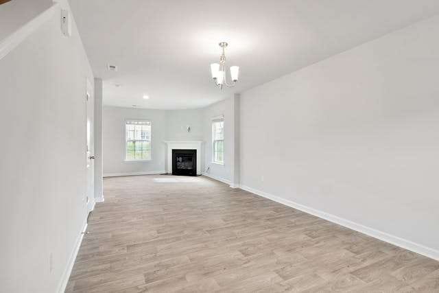 An empty living room with light grey wood-look plank flooring and a corner fireplace.