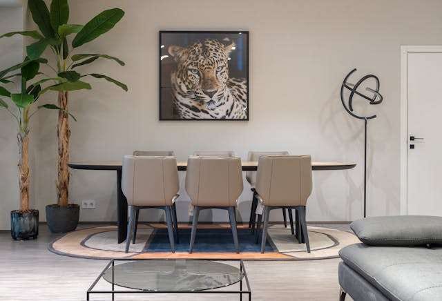 A dining area with a dark table, beige chairs and a light wood-look floor under a round rug.