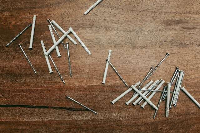 Nails and wall plugs scattered across a dark wood surface.