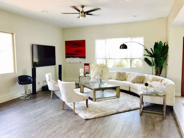 A living room with grey wood-look flooring, a white curved sofa and a shag rug.