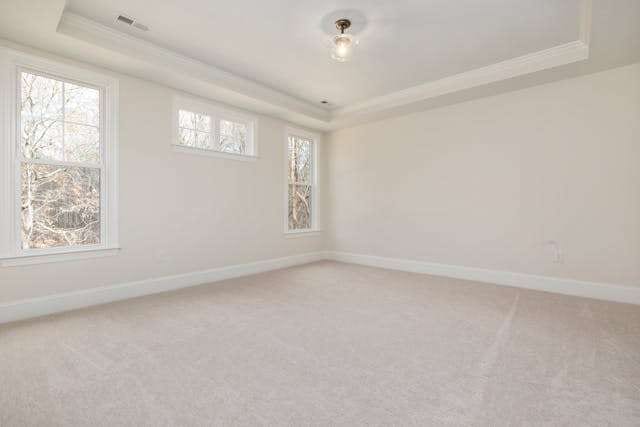 An empty bedroom with light beige carpet and three windows.