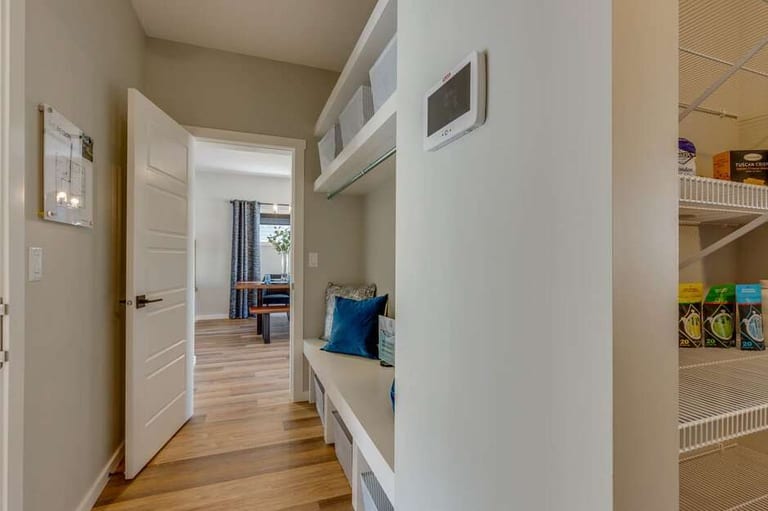 Light wood-look plank flooring in a hallway beside a built-in mudroom bench and open shelving