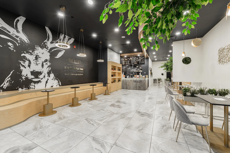 The Alley at West Edmonton Mall: large-format marble-look porcelain tile running through the seating area, under a mural wall and a hanging tree.