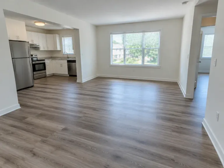 A vacant rental apartment with wood-look vinyl plank flooring throughout and white walls.