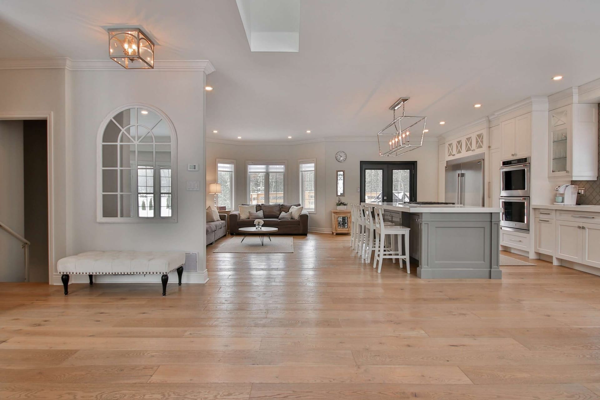 Entry hall looking through to a kitchen, with a light oak floor running the length of the space.
