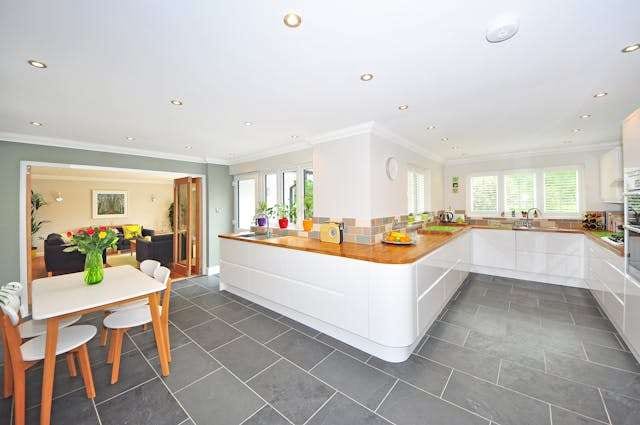 A white kitchen with a curved counter and grey slate-look floor tile.