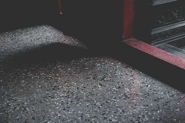 Close-up of a speckled grey epoxy or terrazzo-style floor in low light.