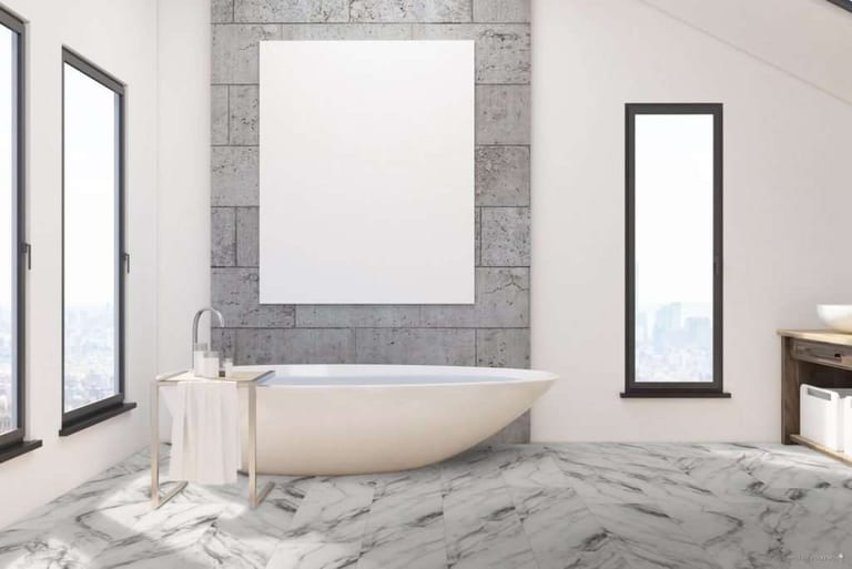 White and grey marble-look tile flooring in a bathroom with a freestanding white tub and a blank framed poster.