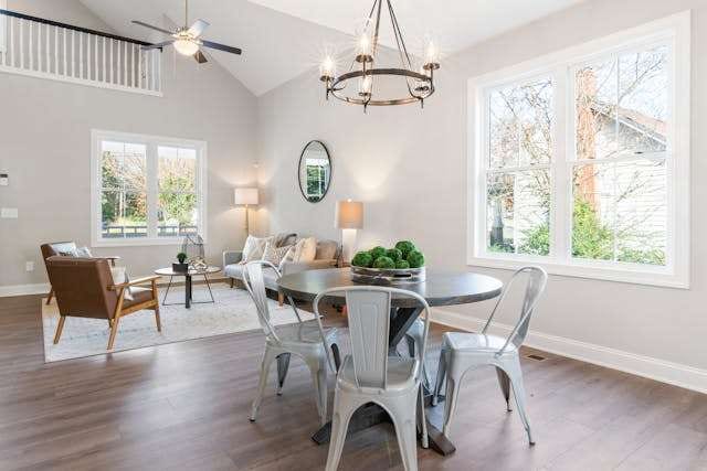 An open living and dining room with grey-brown wood-look flooring, a round table and metal chairs.