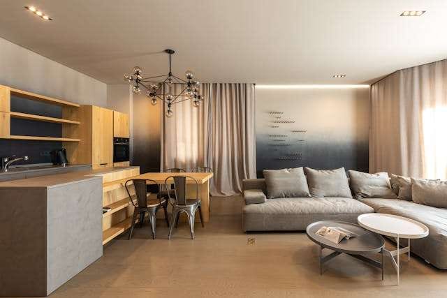 An open-plan kitchen and living room with a pale concrete-look floor and a grey sectional.