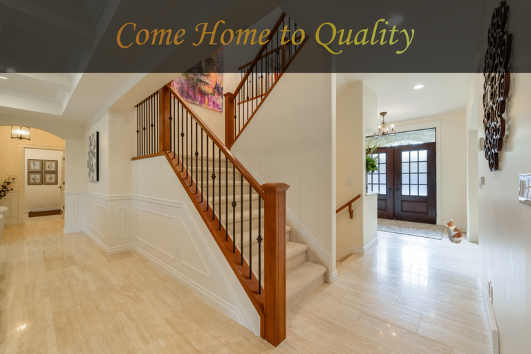 An entryway with a wood-railed staircase and pale flooring, captioned Come Home to Quality