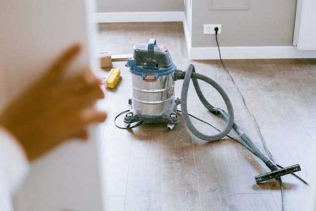 A shop vacuum on a light wood-look floor during a renovation.