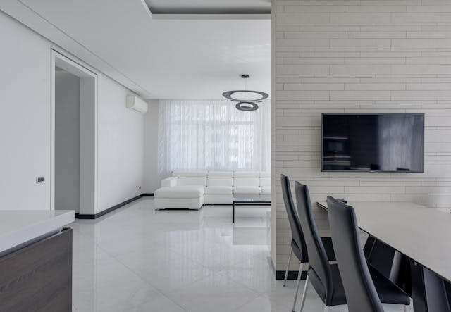 A white open-plan room with glossy white large-format floor tile and a white sectional.