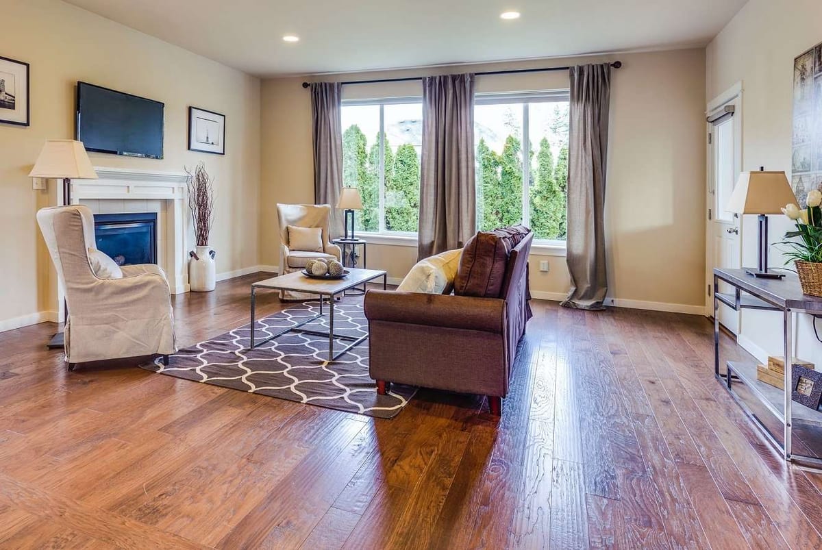 A living room with a medium-brown hardwood floor, a patterned rug and a fireplace.