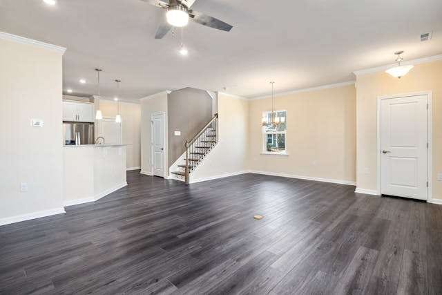 An empty open-plan main floor with dark grey wood-look plank flooring and a staircase.