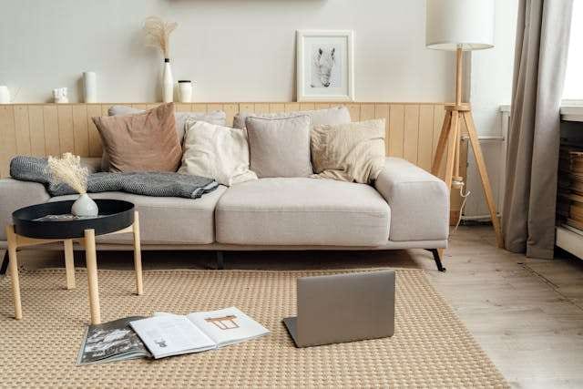 A living room with a beige sofa, a woven jute rug and a light wood floor.