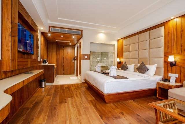 A hotel room with a glossy warm-brown hardwood floor and wood-panelled walls.