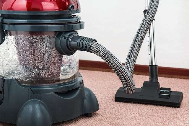 A canister vacuum cleaning pink carpet.
