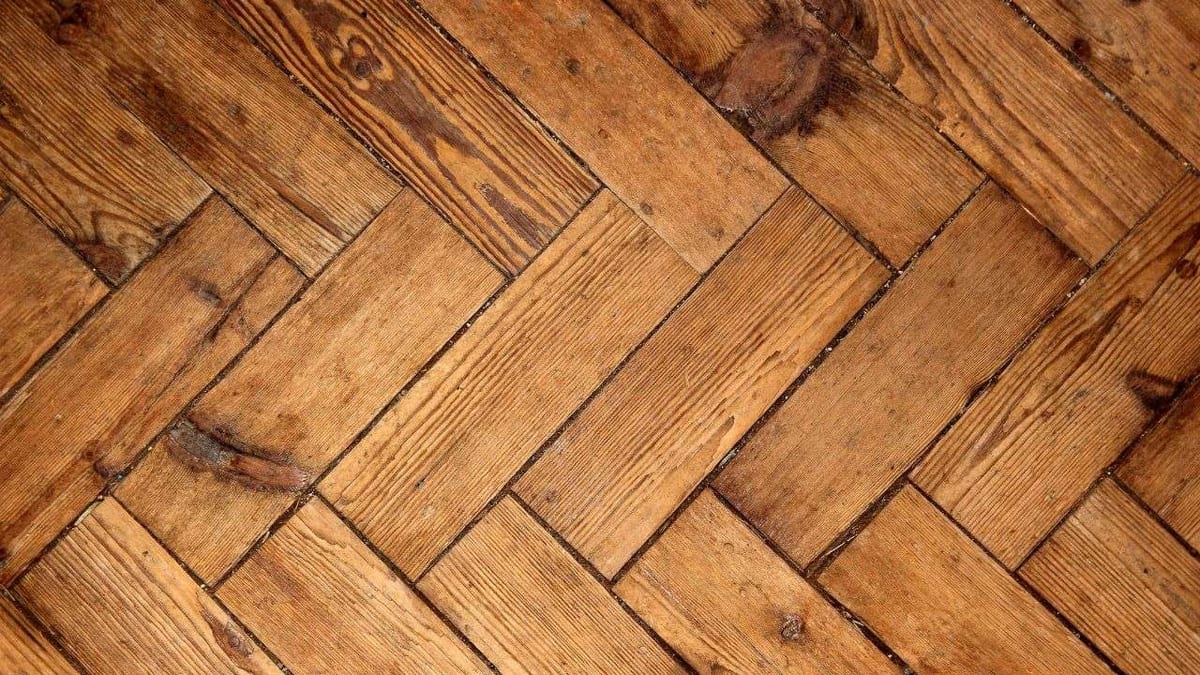 Close-up of rustic wood parquet in a herringbone pattern.