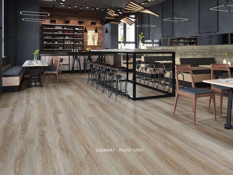 Pale grey wood-look vinyl plank flooring in a restaurant with dark cabinetry and a long bar