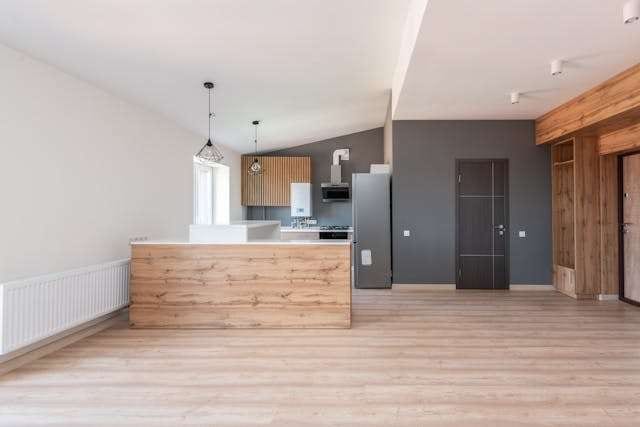 An open kitchen with a wood-clad island and light wood-look plank flooring.