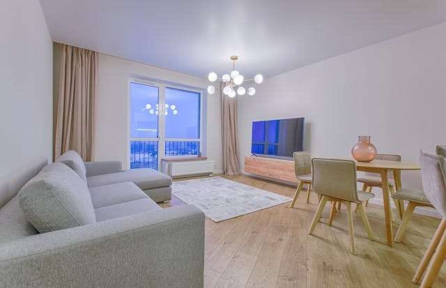 An open living and dining room with light oak-look flooring and a grey sectional.